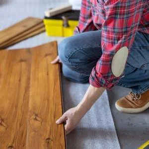 Worker installing laminate wood flooring